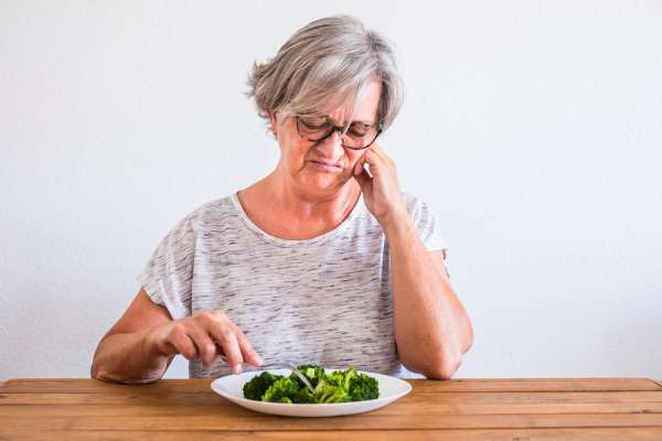 elderly woman with dementia picking at food on plates